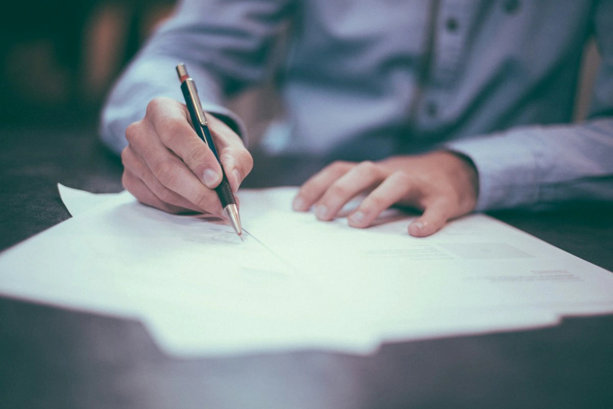 Pessoa revisando documentos e formulários sobre uma mesa de escritório